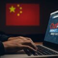 A photo-realistic image shows a person's hands typing on a laptop, with a distorted ChatGPT interface displaying subtly integrated Chinese characters. The person's concerned expression reflects the threat of China's malicious activities using ChatGPT. A dimly lit room with a subtle projection of a Chinese symbol suggests the origin of the threat.