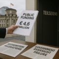 Photorealistic image depicting a hand delivering a stack of papers labeled "Public Funding €4.6 million" toward a dark office door marked "Teilseiend." In the foreground, two newspaper pages on a table read "Antisemitism Allegations" and "Government Oversight Failure." The German Reichstag building is visible in the background, symbolizing state involvement.