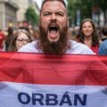 a protester in the Budapest pride parade holds up a banner against Orban and his policies about the LGBTQ community