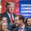 Crowd at National Conservative Conference with a large portrait of Donald Trump in the background and showing the importance of Trump to tnational conservatism as explained by Yorma Hazony