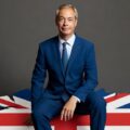 Nigel Farage sitting on a logo of the UK conservative party